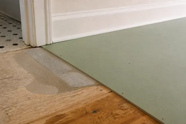 A corrected subfloor transition and fitted underlayment are prepared before finish flooring.